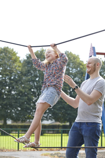 Dad playing with girl on climbing frame