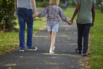 Mum, Dad and girl walking in park