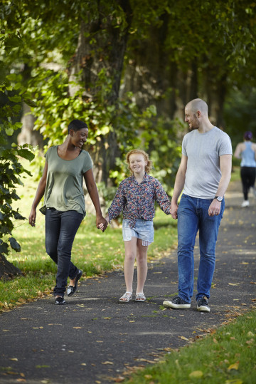 Mum, Dad and girl walking in park