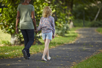 Mum and girl walking in park