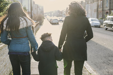 Same sex couple with son walking to school